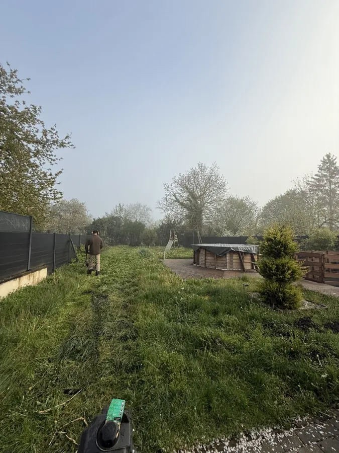 Intervention dans un jardin à l’herbe haute, près d’une terrasse et d’une clôture